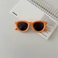 Detail of round orange polarized kids sunglasses on a notebook showing matte texture - Orange