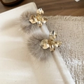 Detailopname van gouden bloemoorringen met pluizige grijsbruine pompon-hangers - Gouden Bloem Grijsbruine Bontbal / Bruin