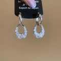 Makro-Detail von silbernen C-Tropfenohrringen mit funkelndem Zirkonia auf Display-Karte - Hohle Tropfen Ohrmanschette (HE28396) / Silber