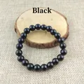 Polished black obsidian beads bracelet with elastic cord on rustic wooden display - 8mm Pure Black