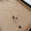Macro detail of silver necklace with tiger eye beads and pavé gender symbol pendant - Silver Zirconia Round Tiger Eye Necklace