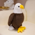 Realistisches Weißkopfseeadler Plüschtier mit braunen Federn auf einem beigen Sofa - 25cm