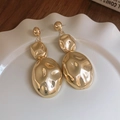 Vista detallada de los pendientes ovalados dorados sobre un plato blanco decorativo - Pendientes - Dorado