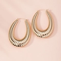 Macro shot of large golden C-shaped hoop earrings with detailed wrinkled wavy texture - Pleated Wave Texture Hoop