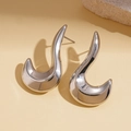 Macro shot of silver wave-shaped earrings with high-polish mirror finish and curved design - Silver