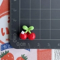 Detailed view of mini red resin cherry accessories with green leaves next to a ruler - Cherry with Small White Flower
