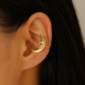 Detailed close-up of a golden crescent moon ear cuff with a smiling face relief design - Moon Ear Clip (S440) / KC Gold