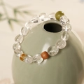 Détail du bracelet en cristal clair avec perles vertes et ambrées sur un vase décoratif - Bracelet en cristal blanc, pierre verte et bois de santal (Coffret cadeau exquis)