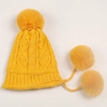 Detail of yellow chunky knit beanie with twisted pattern and three faux fur pom-poms - Yellow