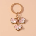 Dettaglio portachiavi dorato con tre ciondoli a cuore in smalto rosa e perle - Rosa