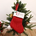 Red knitted Christmas stocking with white cuff featuring embroidered letter U and holly - Letter U