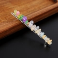 Dettaglio di fermaglio in metallo con scaglie di cristalli naturali colorati su legno - Quarzo crackle colorato con clip d'argento