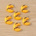 Detail of yellow resin moon pendants with black bat motifs and metal loops for jewelry - Moon