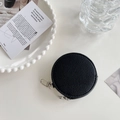 Round black leather coin purse with lychee texture and silver zipper on a decorative tray - Black