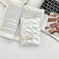 Detalle del organizador de viaje plateado con costuras de corazón sobre un libro de nailon - Corazón Blanco Crema