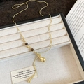 Detailed close-up of golden teardrop necklace with amber beads in a luxury display box - Gold Tiger Eye Beaded Teardrop Necklace