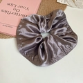 Detail eines grauvioletten Satin-Haargummis mit Metallic-Textur und eleganten Falten - Grau