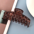 Detail of large tortoiseshell hair claw clip with ink splash pattern on blue surface - Glossy Tortoise Shell 11cm