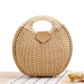 Detailed view of the round straw handbag with a natural weave and leather buckle closure - Tan