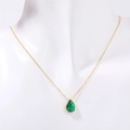 Collana dorata con pendente a goccia di smeraldo su un busto per gioielli bianco - Smeraldo Maggio