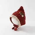 Detail of red knit baby elf hat with lace trim and bow accent on model stand - 6-24 Months / Burgundy