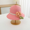 Detailansicht eines rosa Strohhuts mit Stoffblume und gepunktetem Band auf einem Ständer - Hut / Wassermelonenroter Hut