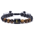 Détail macro du bracelet en œil de tigre et pierre de lave avec lettre dorée E gravée - Style Lettre E