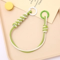 Close-up of hand-woven leather strap keychain with vibrant multi-color contrast design - Green + White