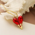 Detail of a red heart pendant with a melting gold effect on a gold box chain - Red