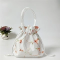 Detail of white satin drawstring pouch with orange floral embroidery and silk handles - White