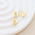 Macro detail of gold-plated square pendant with letter E inlaid with sparkling zircons - Letter E