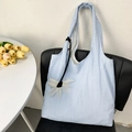 Detail view of light blue pleated tote bag with a white flower charm on a black chair - Flower Charm Style / Blue
