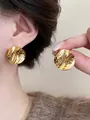 Detailed macro view of 18k gold plated pleated round stud earrings with unique texture - Gold