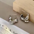 Detailed view of silver irregular liquid metal earrings on minimalist wooden props - 22# Steel Needle Pleated V-Shape Stud Earrings