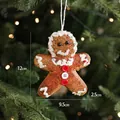 Gingerbread man ornament with white icing details and colored buttons on Xmas tree branch - Gingerbread Man