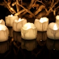 Detail of white LED tea light candles with warm yellow flames and melted wax texture - Standard Function / Warm White Flickering