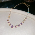 Macro detail of gold necklace with pink purple zircons and sparkling starburst light - Necklace - Gold - Pink