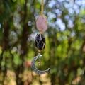 Close-up of pink and purple raw crystals in woven nets with silver moon and star pendant - Rose Quartz + Amethyst (Silver Accessories)