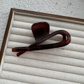 Close-up of a large tortoiseshell hair claw clip with twisted design on velvet display tray - Matte Reddish Brown