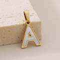 Colgante letra A bañado en oro de 18K con nácar blanco sobre superficie de piedra - Estilo Letra A