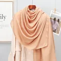 Close-up of lightweight apricot cotton linen scarf draped over a beige blazer - Khaki