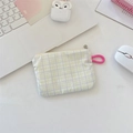 Close-up of green checkered small storage pouch for earphones and coins on office desk - Soft Purple Plaid