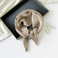 Detail of champagne gold pleated silk scarf tied in a bow on an elegant flat lay display - 70*70cm / Pleated Champagne