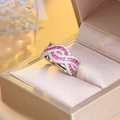 Macro detail of intertwined silver ring featuring pink rubies and sparkling white zircons - Red