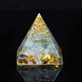 Orgone pyramid with blue and white crystals and golden coil on a reflective black base - Aquamarine