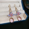 Details von Blumenohrringen mit rosa und blauen Kristallen und Tropfenanhänger in einer Box - Rosa