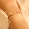 Close-up of a minimalist gold safety pin bracelet worn on a wrist with soft lighting - KC Gold Pin Bracelet (DZ-360)