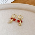 Detailaufnahme goldener Erdnuss-Ohrhänger mit roten Perlen auf einem Tablett - Goldene Erdnuss mit roten Perlen / Creolen - Gold & Rot