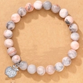 Pink zebra stone bead bracelet with a crystal-studded silver apple charm on textured background - Pink Apple Rhinestone