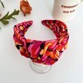 Detail of colorful bohemian floral print knotted headband for women on a minimal stand - Red Printed Wide Knotted Headband
